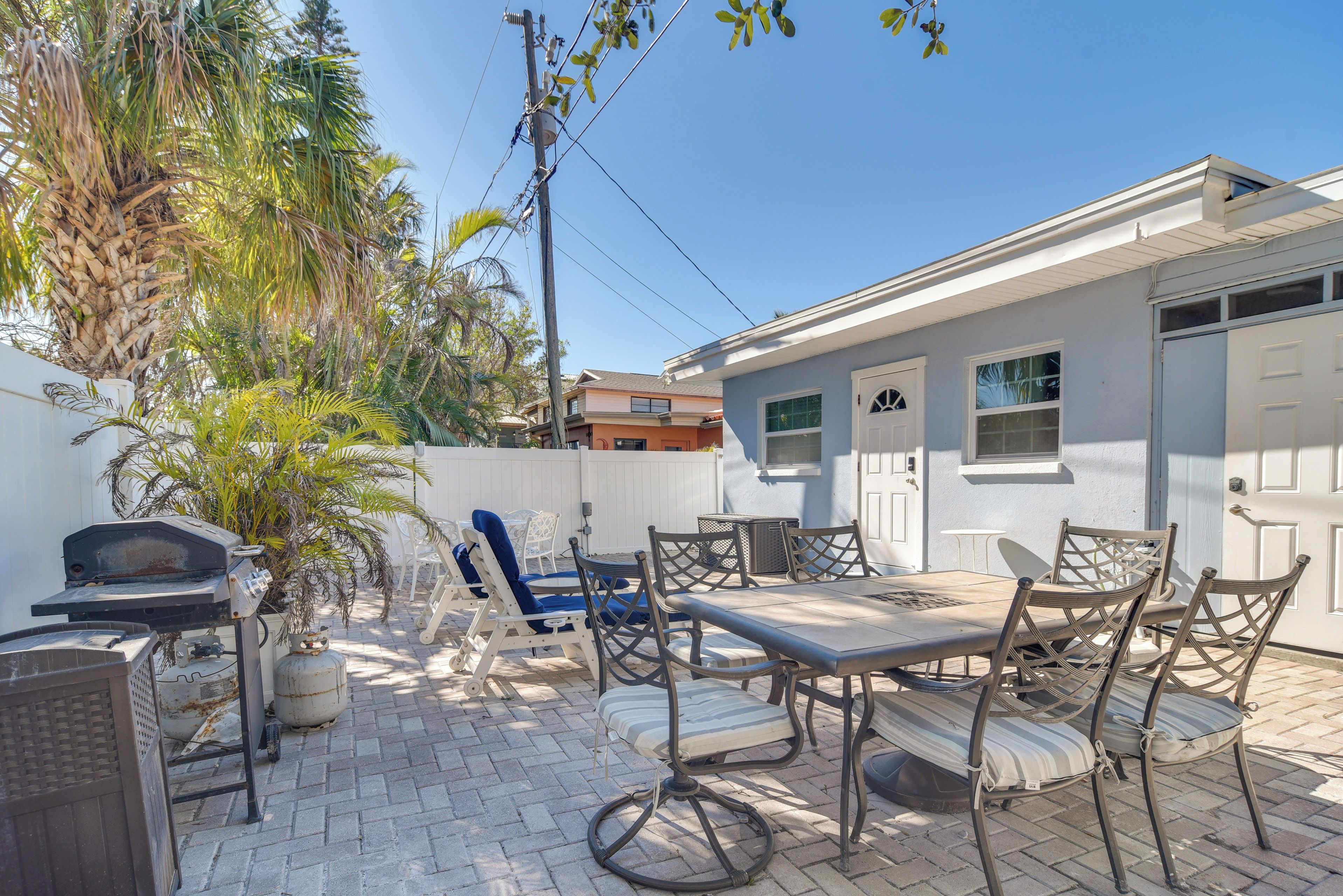 Un patio con mobiliario exterior, una parrilla y una palmera.
