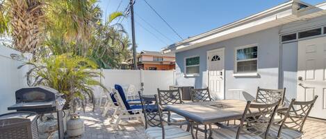 A patio with outdoor furniture, a grill, and a palm tree.
