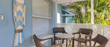 A covered outdoor seating area with wicker chairs and a surfboard decoration.