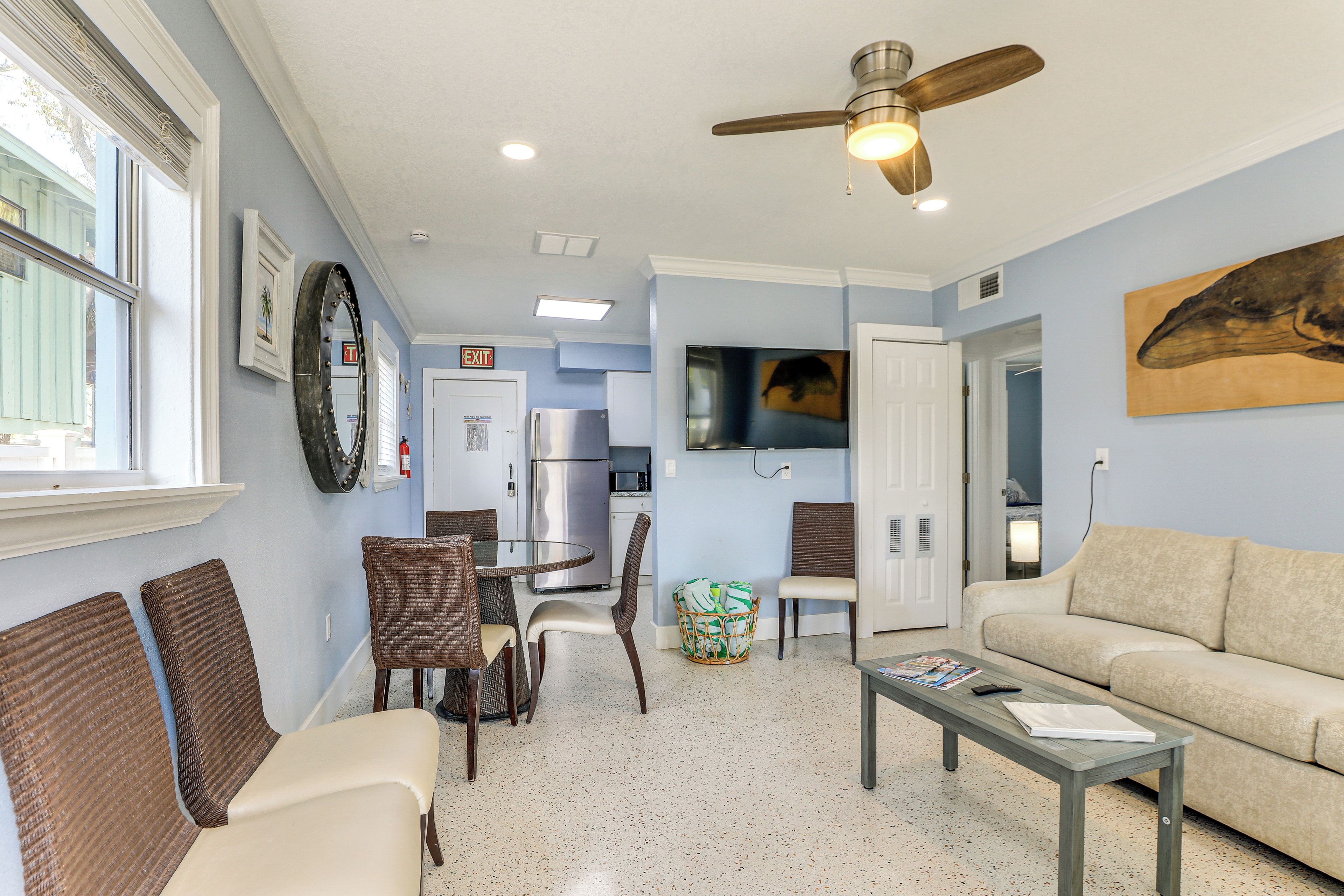 A living room with a sofa, a coffee table, and a dining area with chairs and a table.