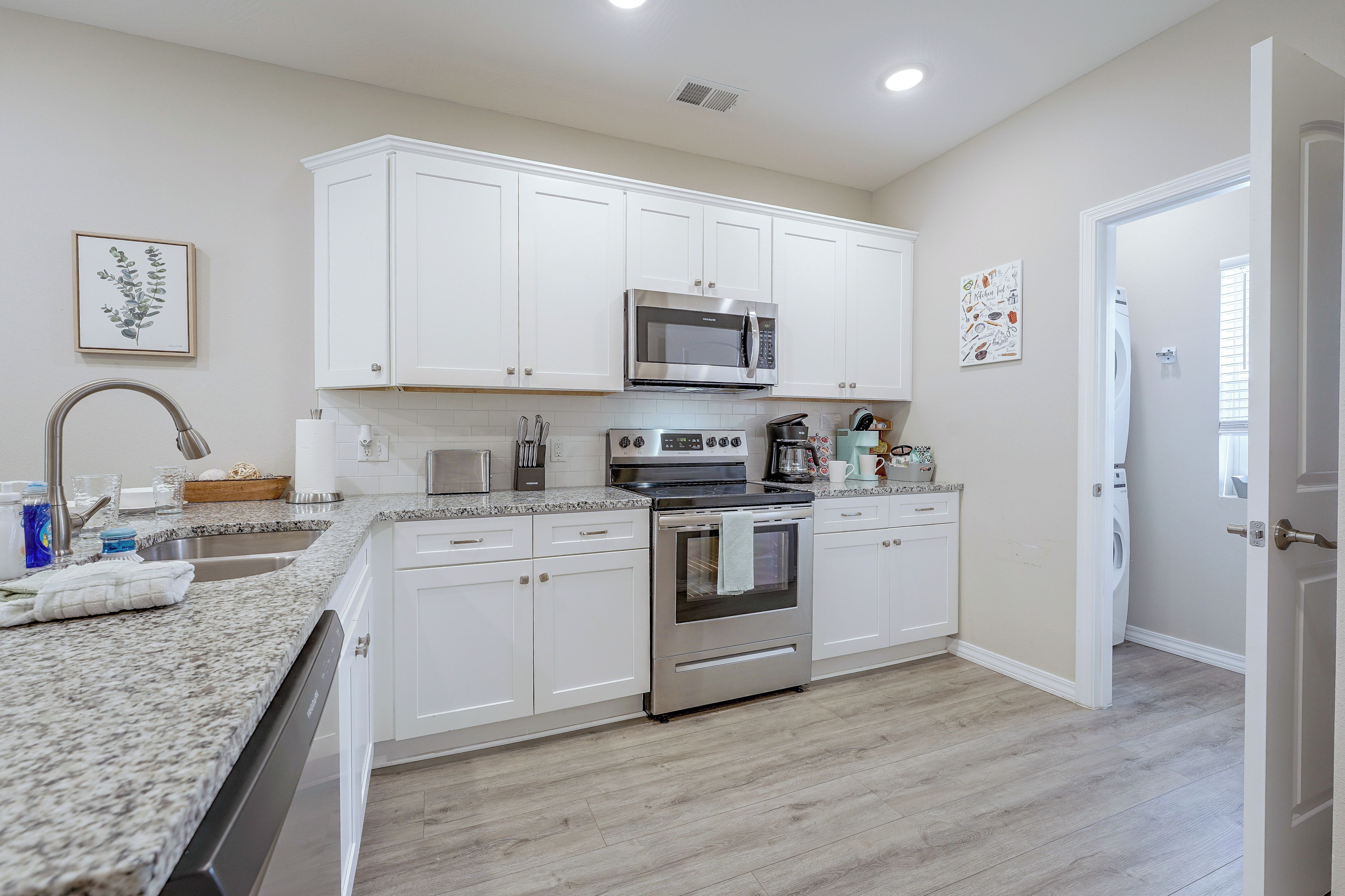 A modern kitchen with white cabinets, stainless steel appliances, and a granite countertop.