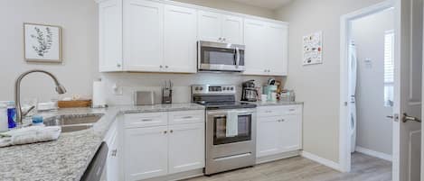 A modern kitchen with white cabinets, stainless steel appliances, and a granite countertop.