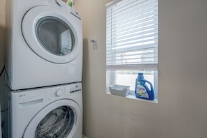 A laundry area with stacked washing machines and a window with blinds. - Condo Near Branson Strip: Close to It All! (Branson)