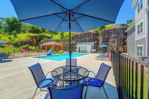 A pool area with a covered seating area, lounge chairs, and a small building. - Condo Near Branson Strip: Close to It All! (Branson)