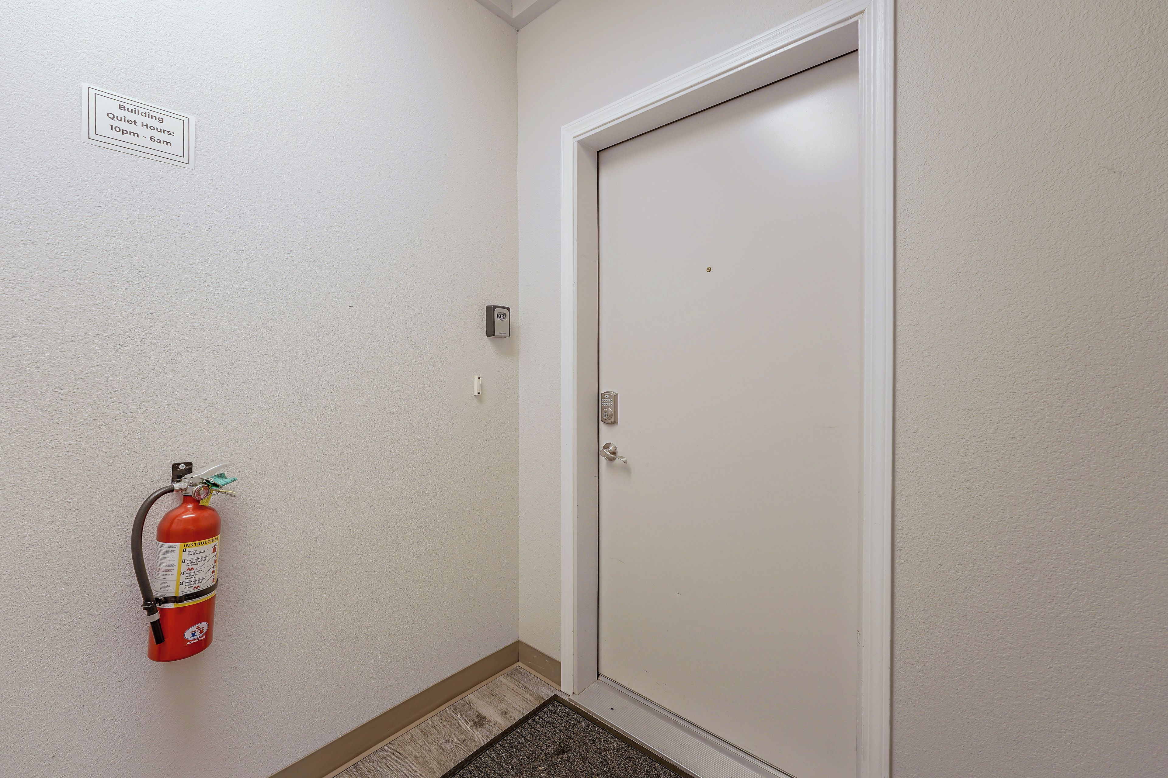 A door with a fire extinguisher mounted on the wall and a sign indicating quiet hours.