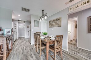 A dining area with a wooden table and chairs, a chandelier, and a 'Welcome' sign on the wall. - Branson Condo Near Shows, Dining & Table Rock Lake (Branson)