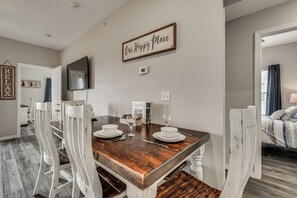 Un coin repas avec une table en bois, des chaises blanches et un panneau sur lequel on peut lire : « Notre endroit préféré ».