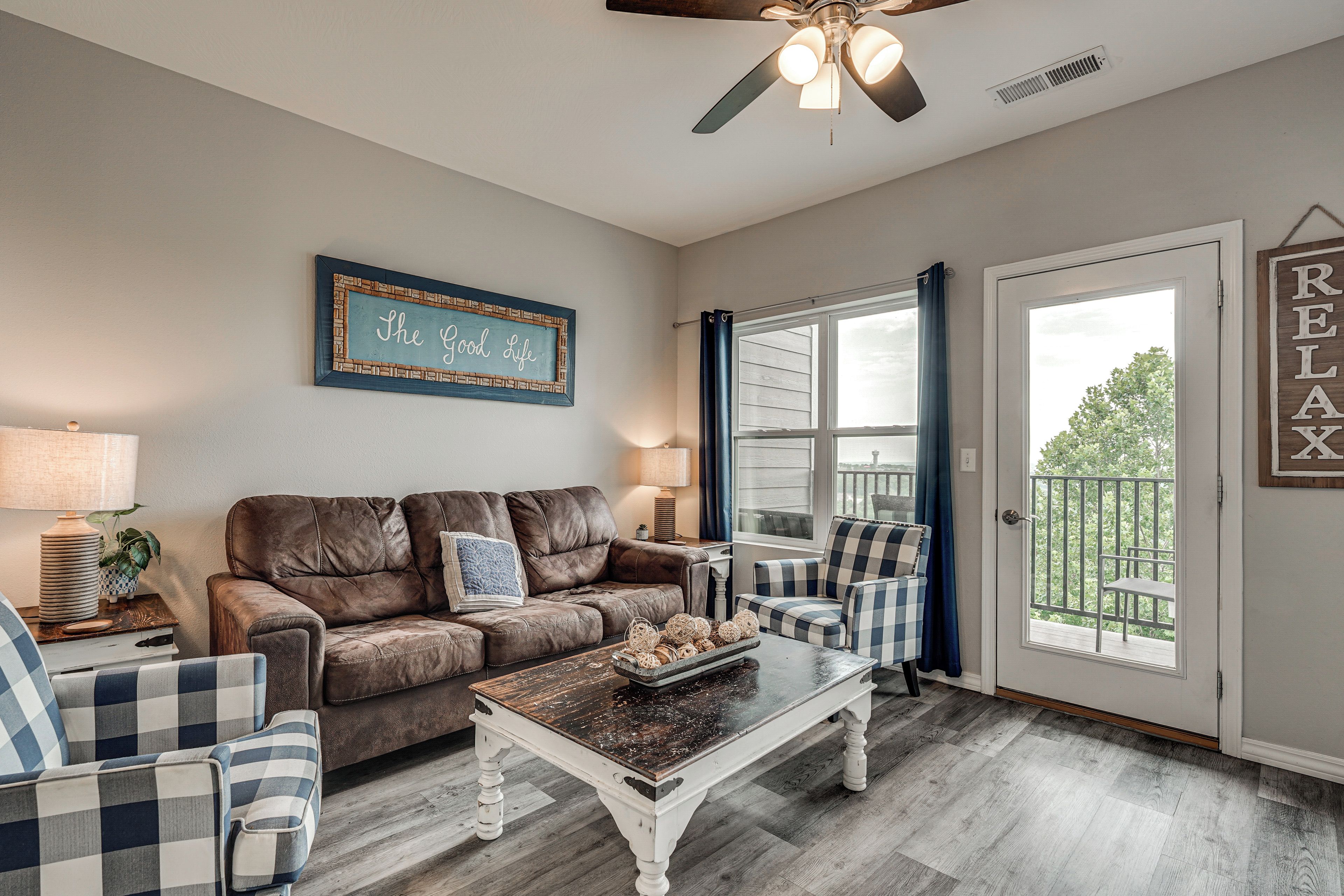 A living room with a brown leather sofa, two plaid armchairs, a coffee table, and a ceiling fan.
