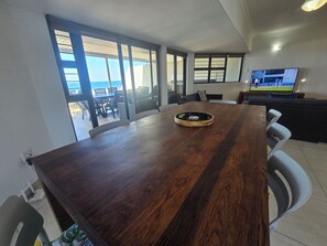 Zona pranzo con un tavolo di legno, sedie e un televisore su un mobile.