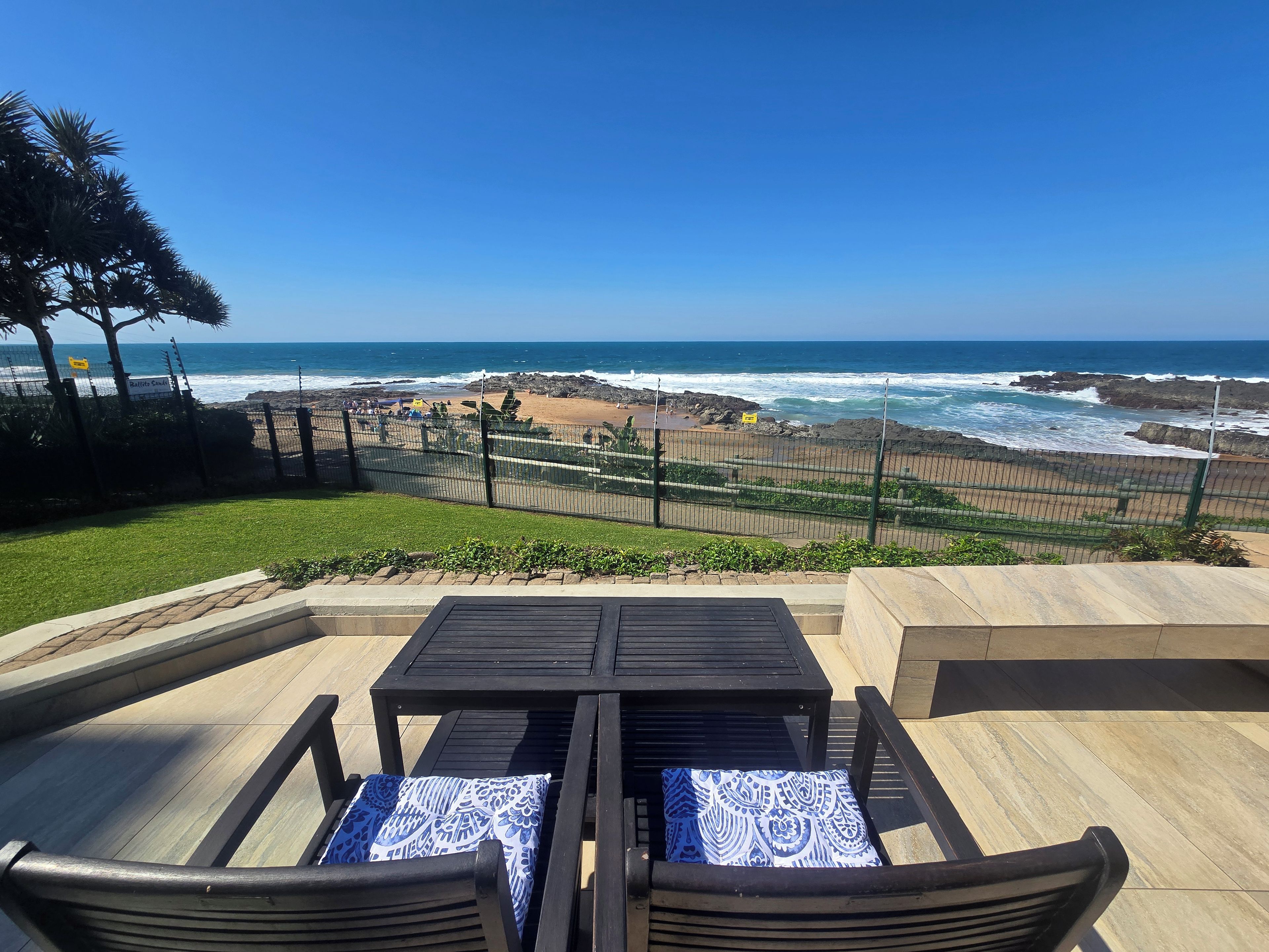 Un área de estar al aire libre con vista al océano y una playa rocosa.