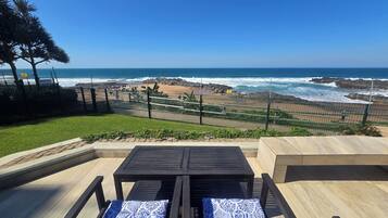 Un área de estar al aire libre con vista al océano y una playa rocosa.