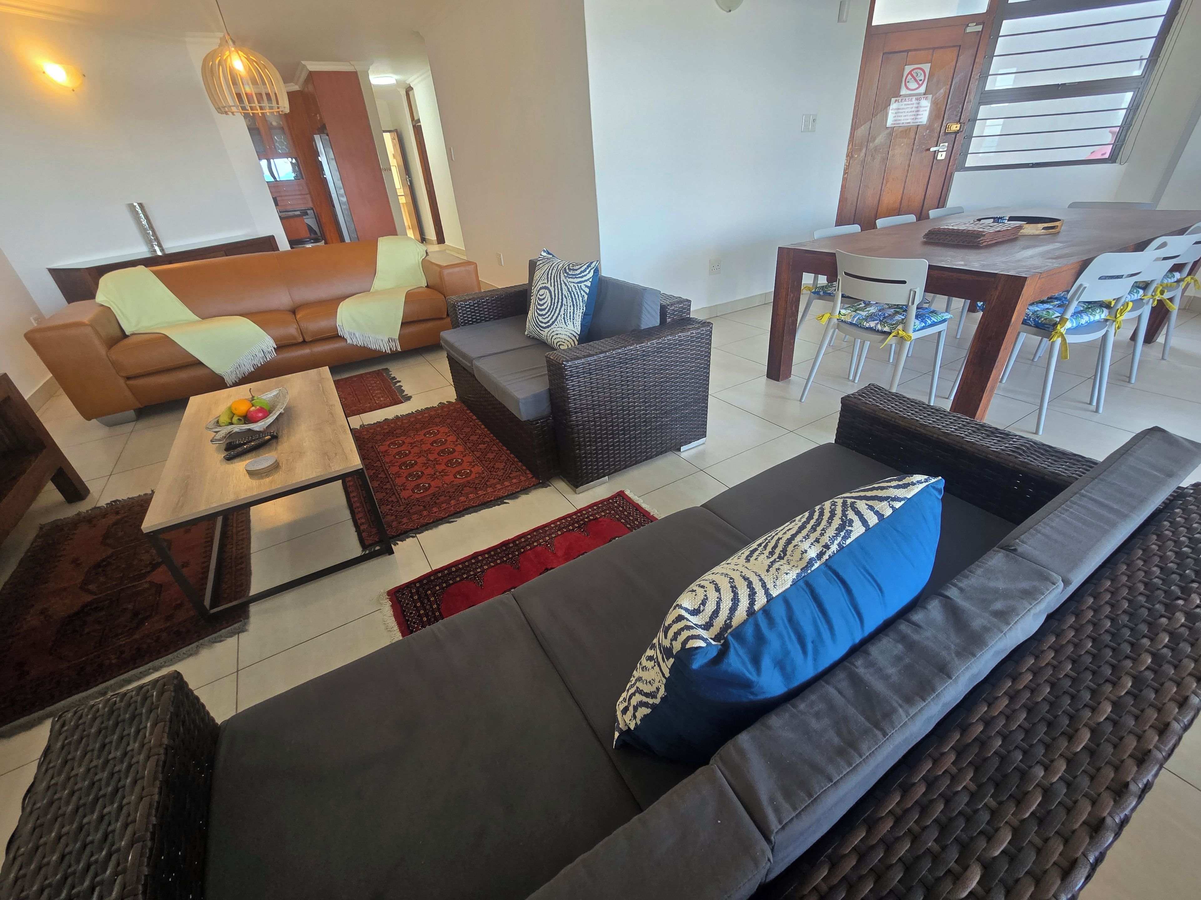 A living room with a sofa, armchairs, a coffee table, and a dining area with chairs and a table.