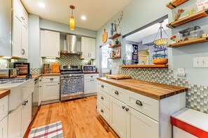 A modern kitchen with white cabinetry, a wooden countertop, and a tiled backsplash.