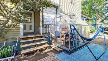 A house with a greenhouse, wooden steps, and a blue hammock.