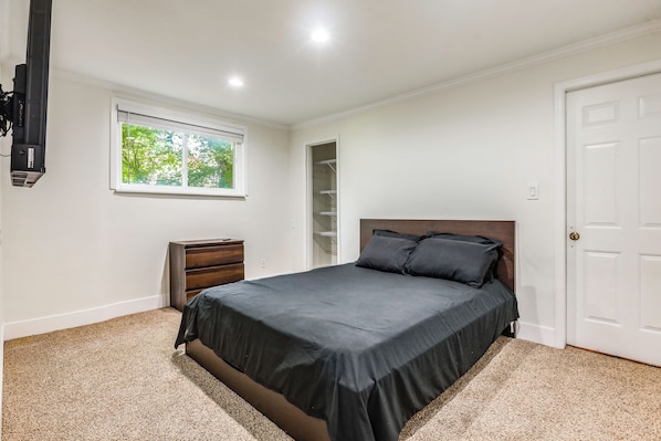 A bedroom with a bed, a dresser, a window, and a door. - Cincinnati-area Condo: Near Shops & Dining (Cincinnati)