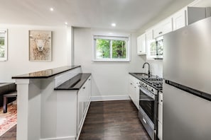 A modern kitchen with white cabinetry, a black countertop, and a stainless steel stove. - Cincinnati-area Condo: Near Shops & Dining (Cincinnati)