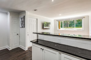 A kitchen with white cabinets, a black countertop, and a window with a view of greenery. - Cincinnati-area Condo: Near Shops & Dining (Cincinnati)