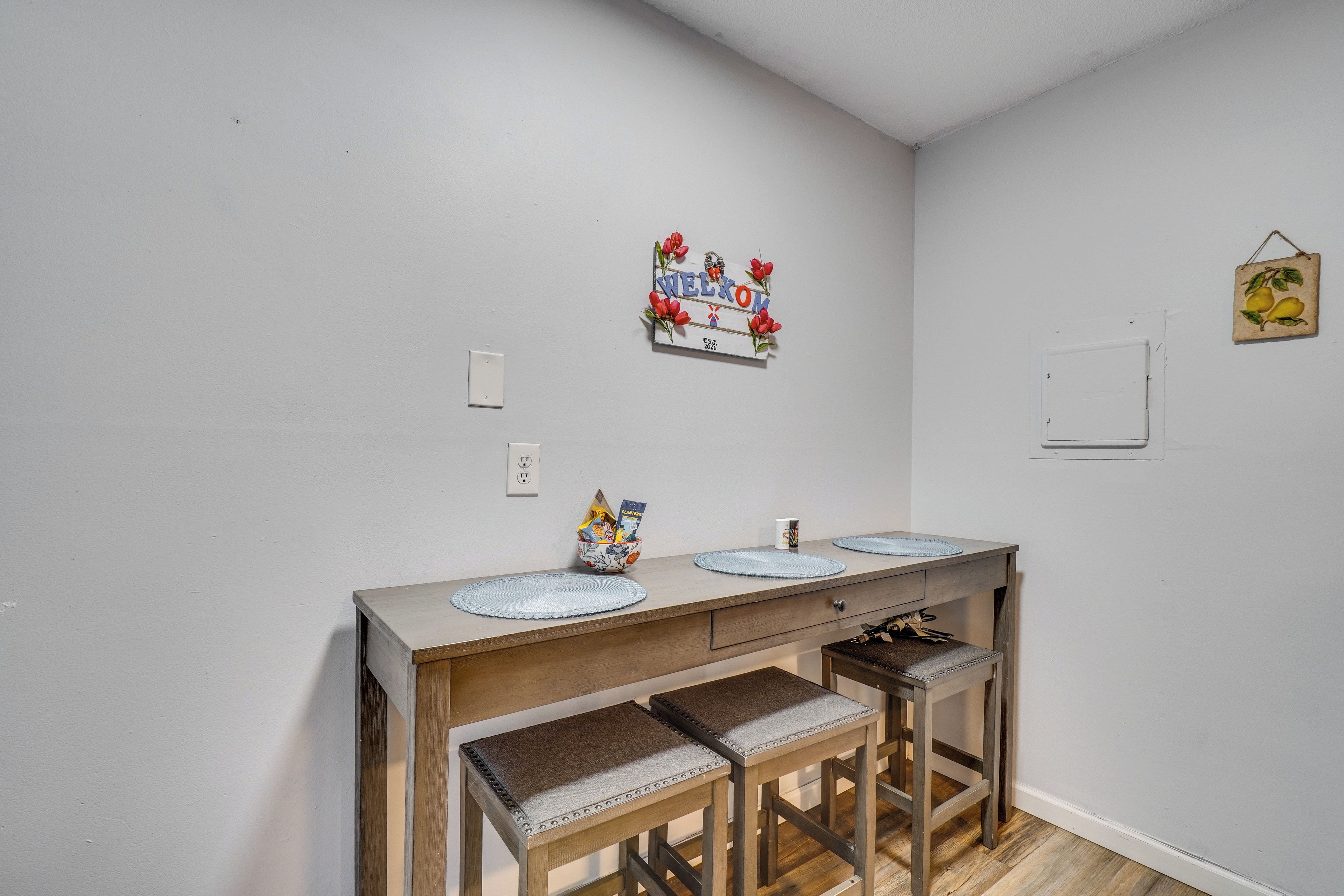 A kitchen with a wooden countertop, three barstools, and a wall-mounted sign.