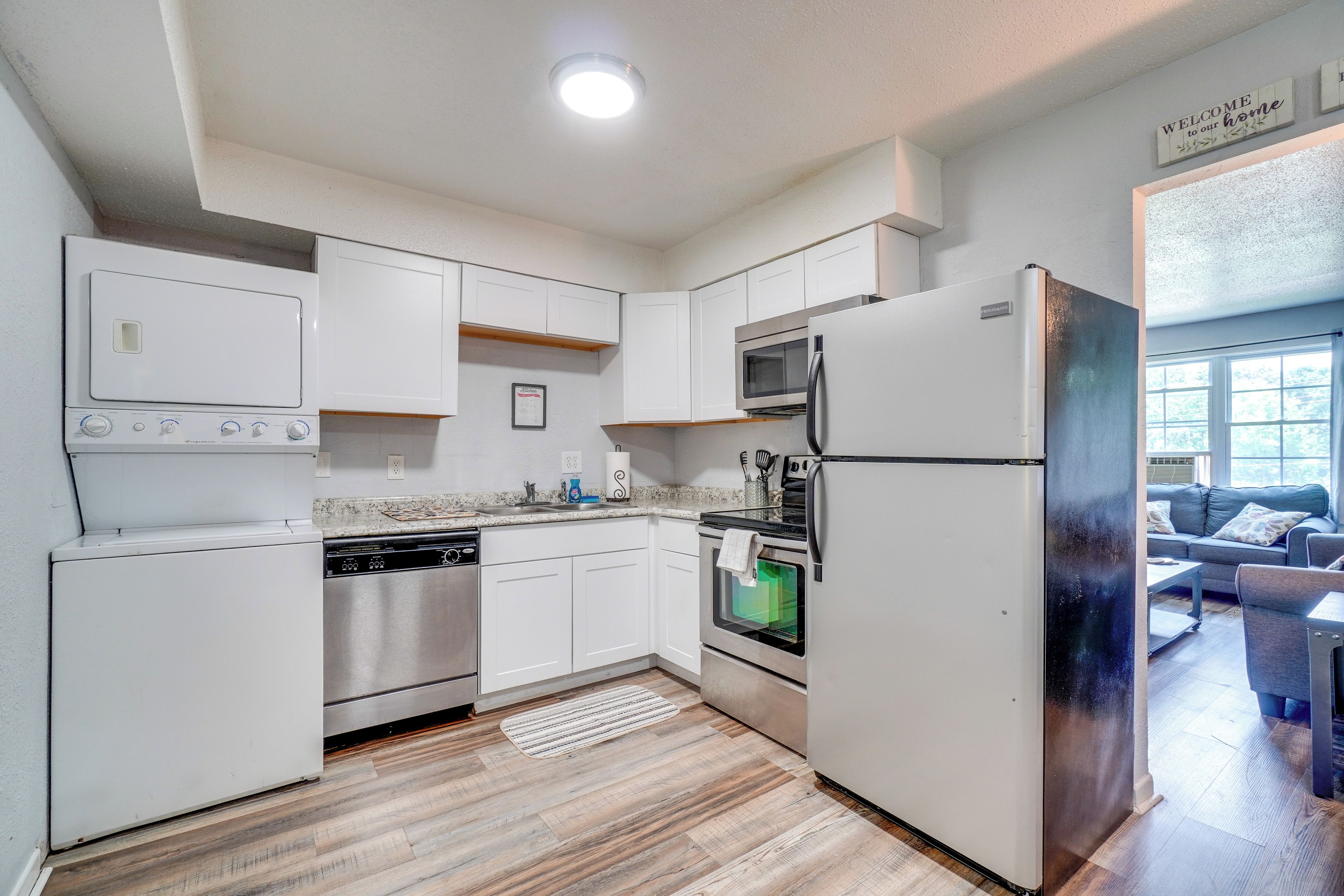 A modern kitchen with white cabinetry, stainless steel appliances, and a wooden floor.