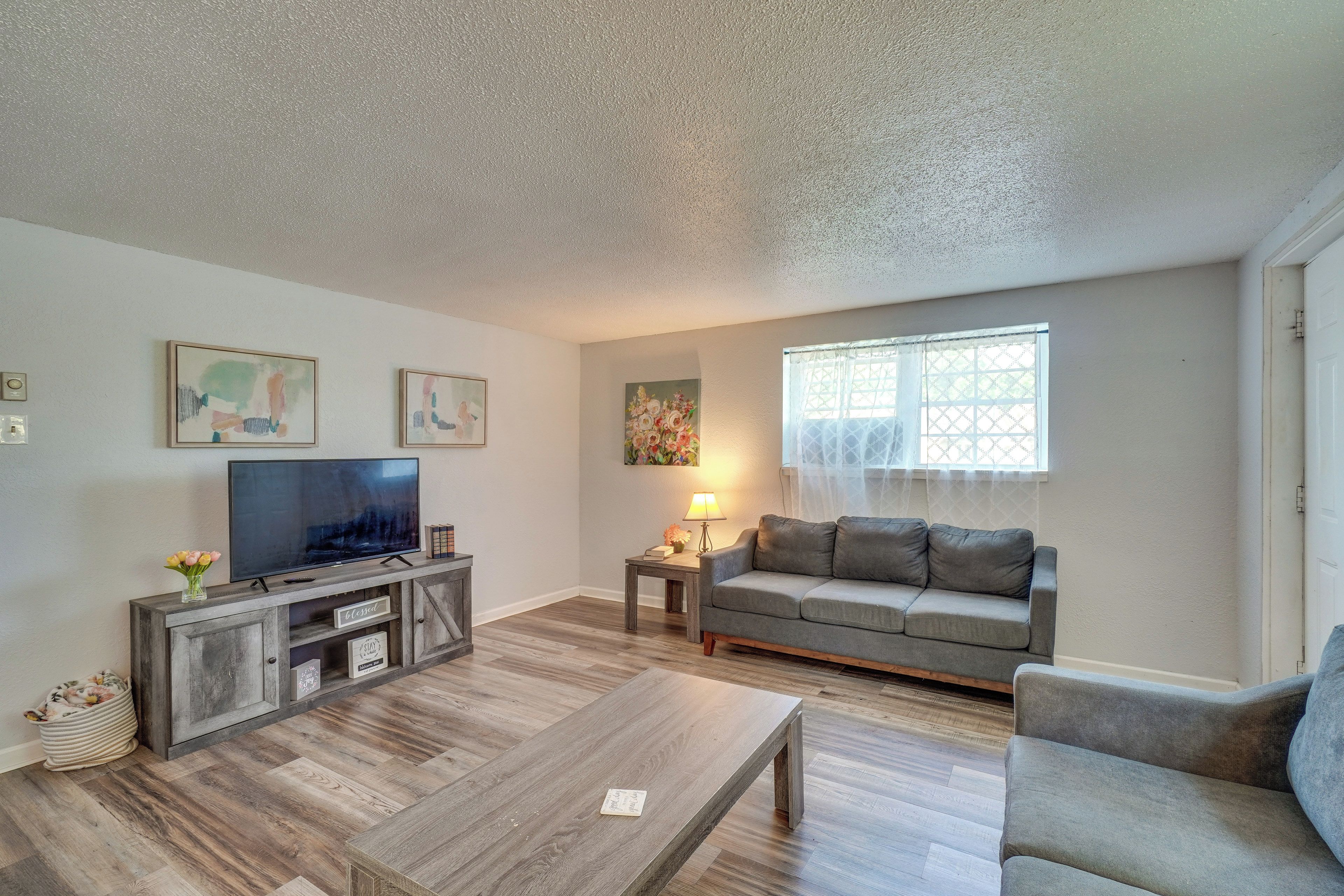 A living room with a TV, sofa, coffee table, and artwork on the walls.