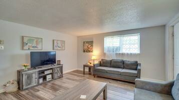 A living room with a TV, sofa, coffee table, and artwork on the walls.