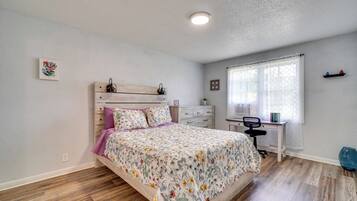 A bedroom with a bed, a desk, and a chair.
