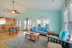 Un salón amplio con un sofá azul, una mesa de comedor de madera y sillas.