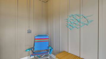 Una habitación con una silla de playa a rayas, un banco de madera y un adorno en la pared.