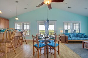 Una habitación amplia con zona de comedor, un sofá y vistas al exterior.