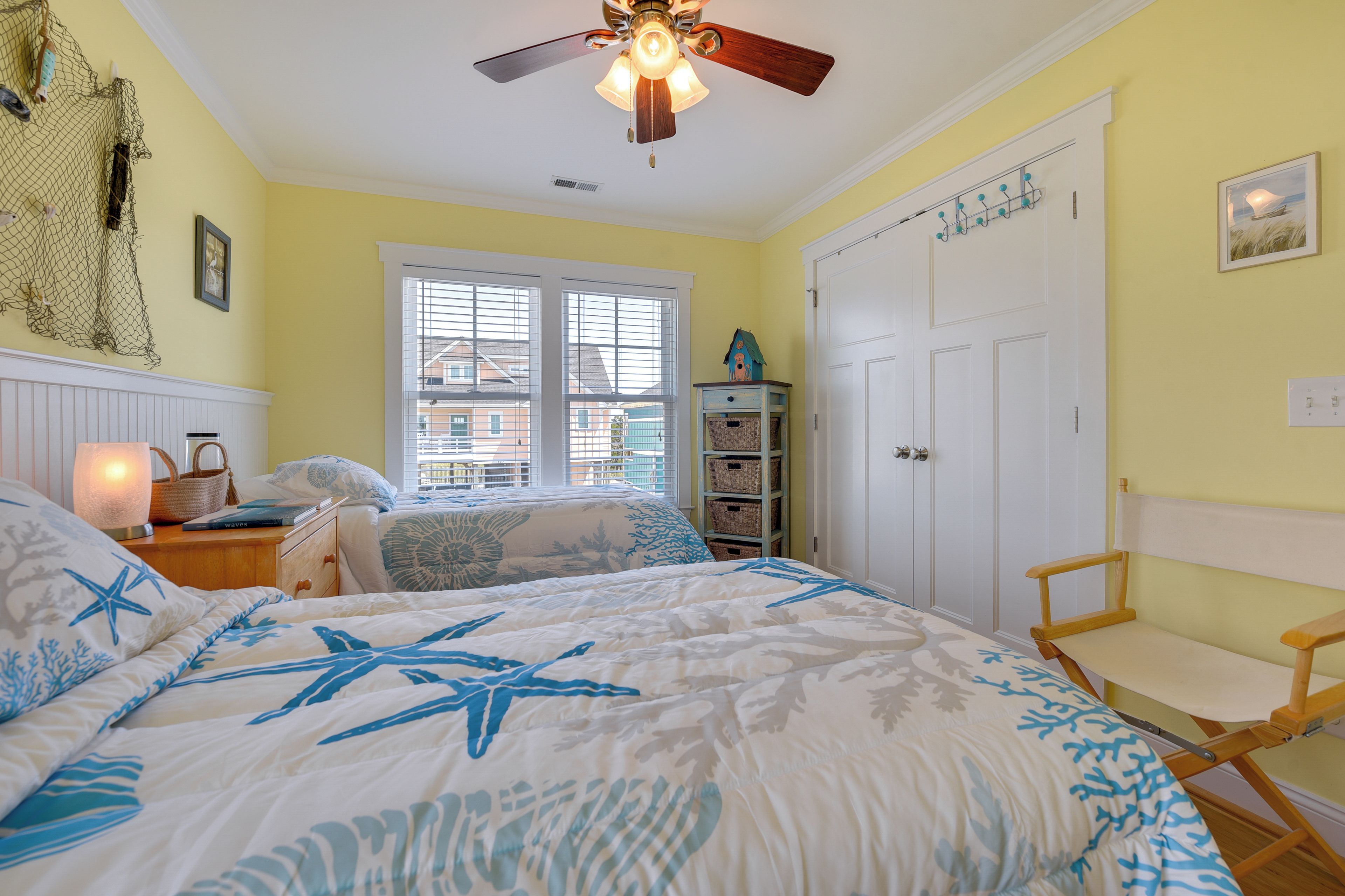 A bedroom with a bed, a ceiling fan, a window, and a door.