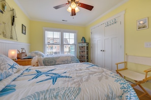 A bedroom with a bed, a ceiling fan, a window, and a door. - Sunset & Waterway Views! Holden Beach Getaway (Supply)