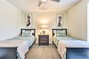Ein Schlafzimmer mit zwei Betten, einem Nachttisch mit Lampe und Wandbildern.