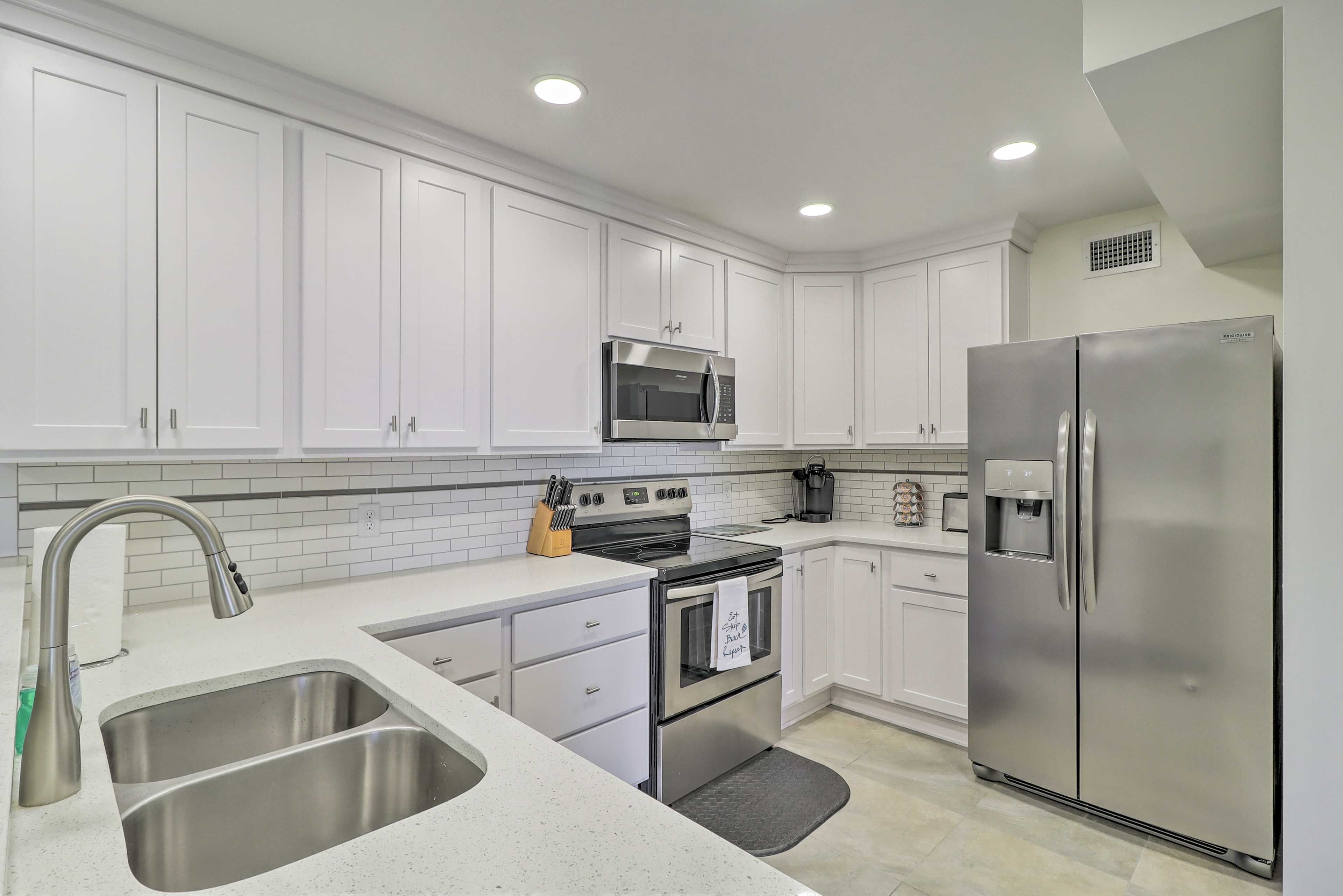 A modern kitchen with white cabinetry, stainless steel appliances, and a built-in oven.