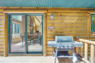 Una cabaña de madera con puerta de vidrio, una parrilla para barbacoa y un cartel que dice 'SHHH BEARS NAPPING'.