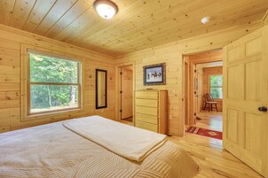 Un dormitorio de cabaña de madera con una cama, cómoda y un cuadro en la pared.