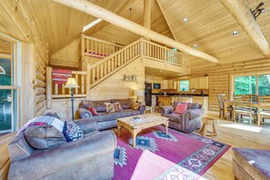 A spacious log cabin interior with a living area, kitchen, and a staircase leading to an upper level. - Ski, Hike & Explore! Spacious Conway Cabin w/ Deck (Conway)