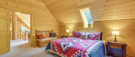 Un dormitorio tipo cabaña de troncos con una cama, mesitas de noche, un banco y una ventana.