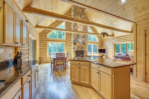 Un interior espacioso de cabaña de madera con un amplio comedor, cocina y una zona de estar acogedora.