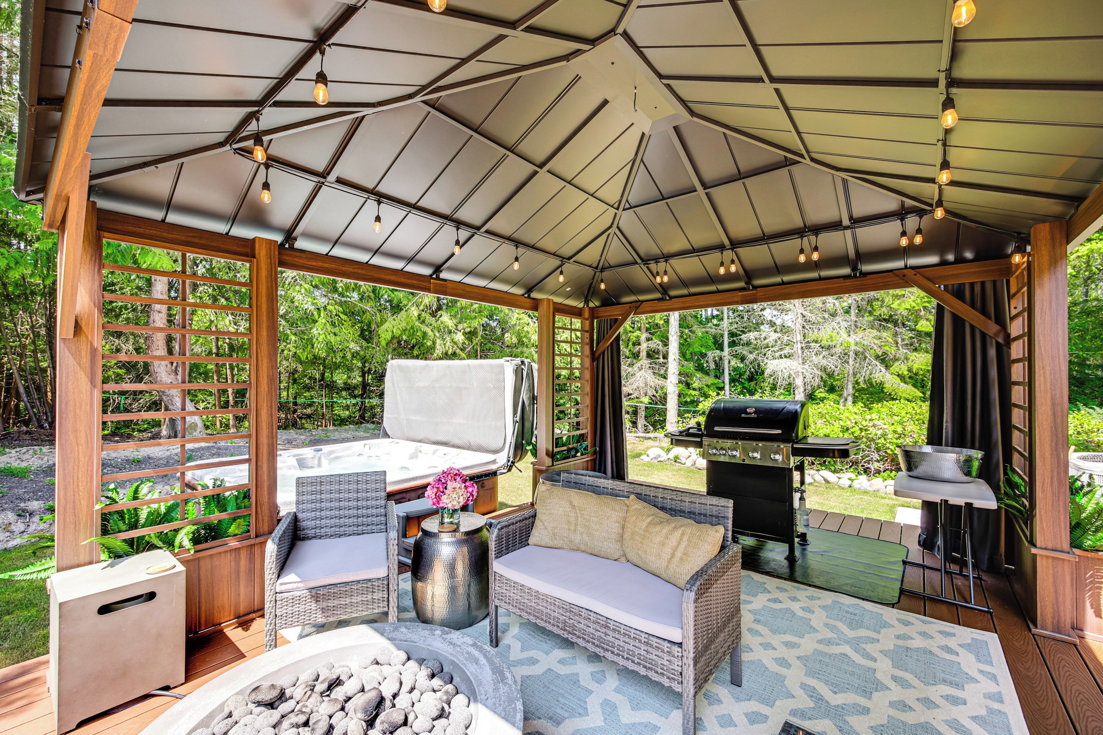 A covered outdoor seating area with a grill, a sofa, and a table.