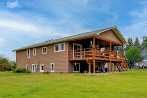 A two-story house with a wooden deck and a covered porch. - Riverfront Group Getaway Near Glacier NP (Columbia Falls)