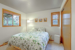 A bedroom with a bed, two windows, a standing lamp, and a radiator. - Riverfront Group Getaway Near Glacier NP (Columbia Falls)