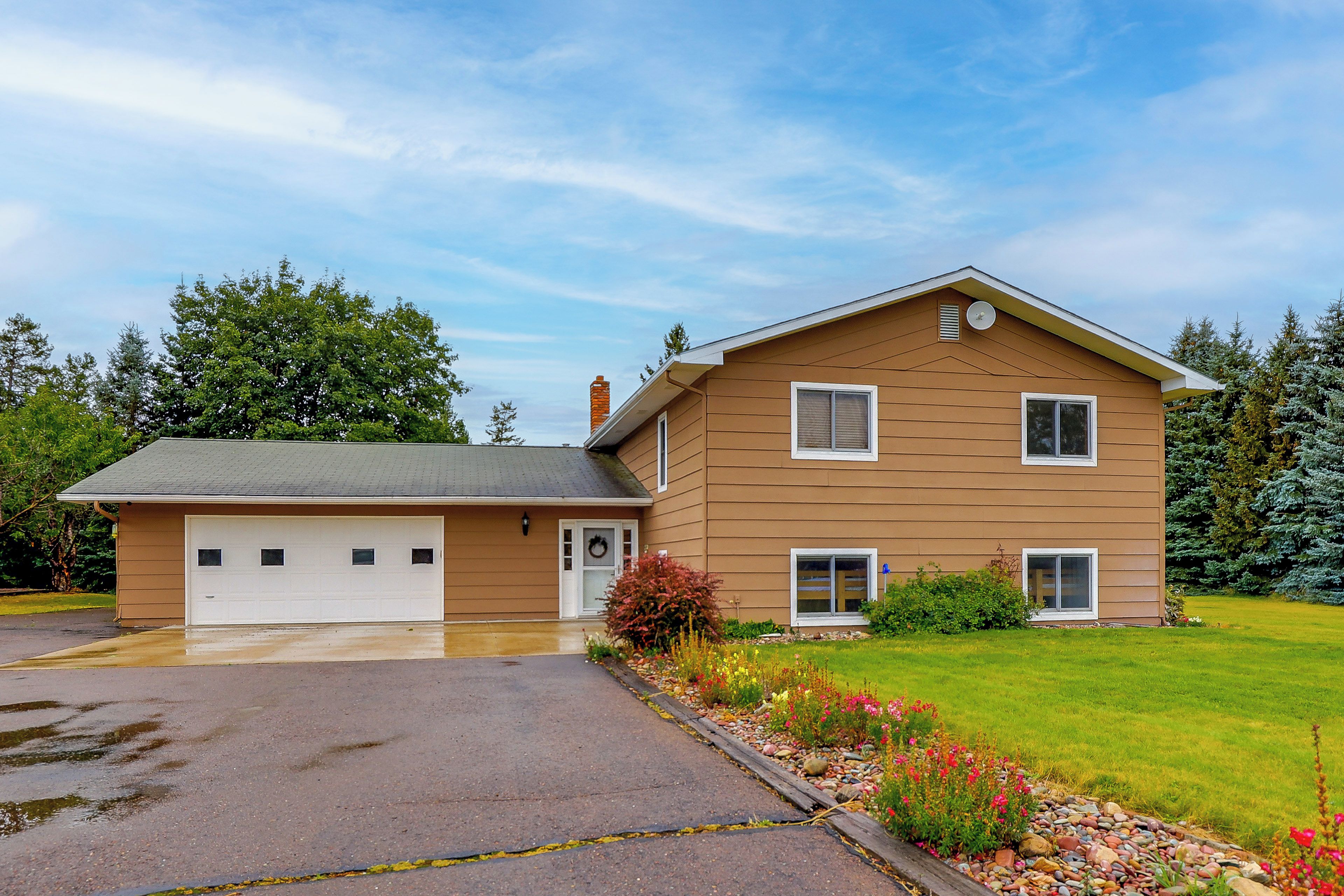 A two-story house with a garage, a front porch, and a well-maintained lawn.
