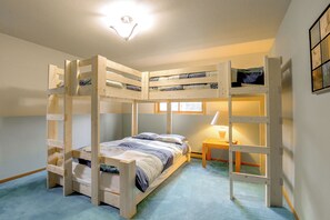 Ein Mehrbettzimmer mit Schreibtisch und Lampe.