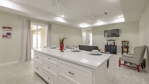 Une cuisine moderne dotée d’un grand îlot central, de meubles blancs et d’un ventilateur de plafond.