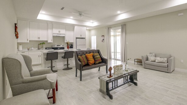Un salon moderne comprenant un canapé, des fauteuils, une table basse et un coin repas, avec une cuisine en arrière-plan.