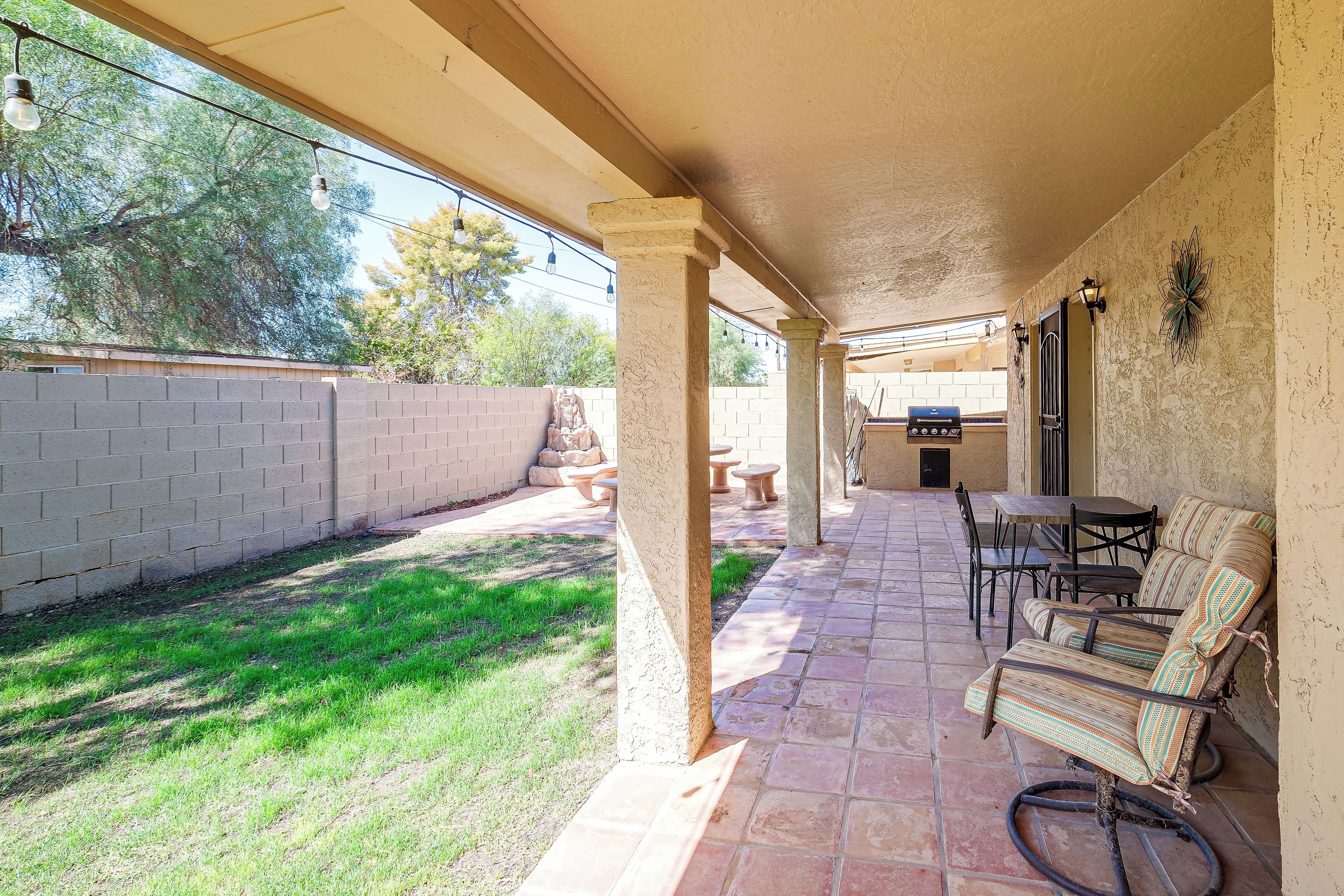 A covered patio area with outdoor seating, a barbecue grill, and a view of the backyard.