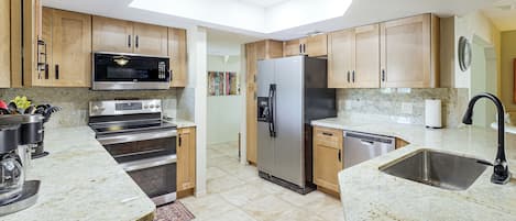 A modern kitchen with granite countertops, stainless steel appliances, and wooden cabinets.