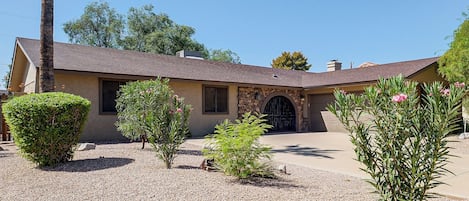 A single-story house with a stone facade, a tiled roof, and a gravel driveway.