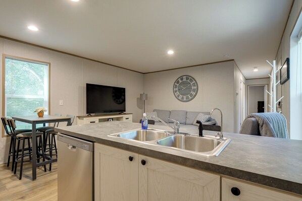 A modern kitchen with a built-in dishwasher, a large sink, and a flat-screen TV.