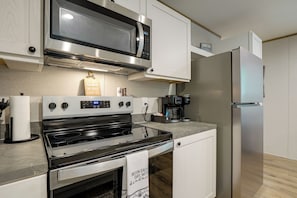 Una cocina moderna con electrodomésticos de acero inoxidable, incluyendo un microondas, horno y refrigerador.